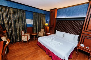 A hotel room with a large bed, two chairs, a small table, and a lamp. - Hotel San Marco (General Santos)