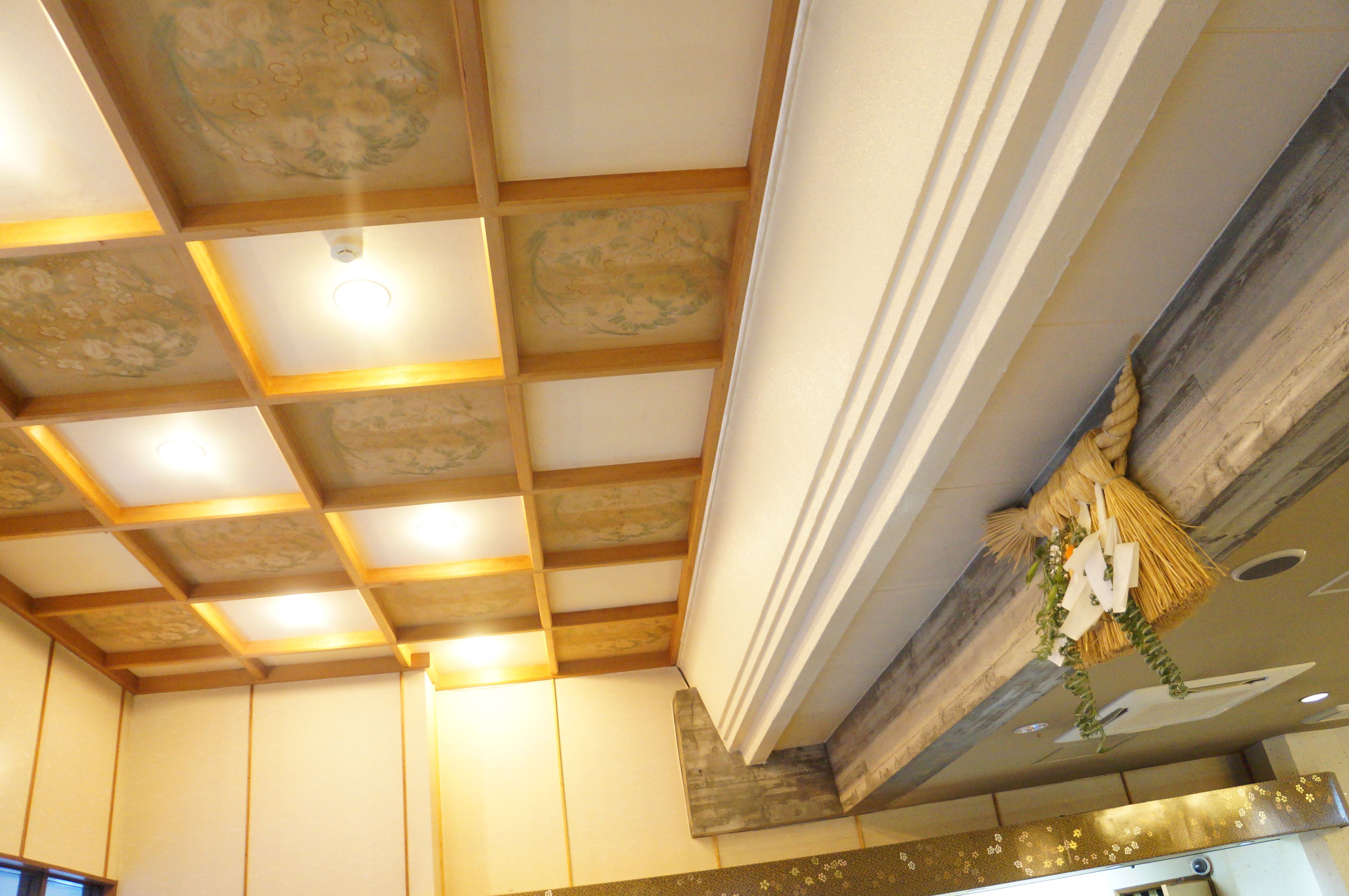Une pièce dotée d’un plafond en bois et d’un mur décoratif agrémenté d’un panier tressé et de plantes vertes.