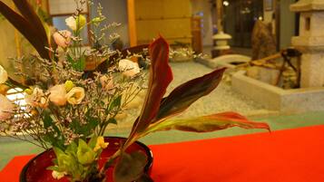 A red vase with a floral arrangement on a table.