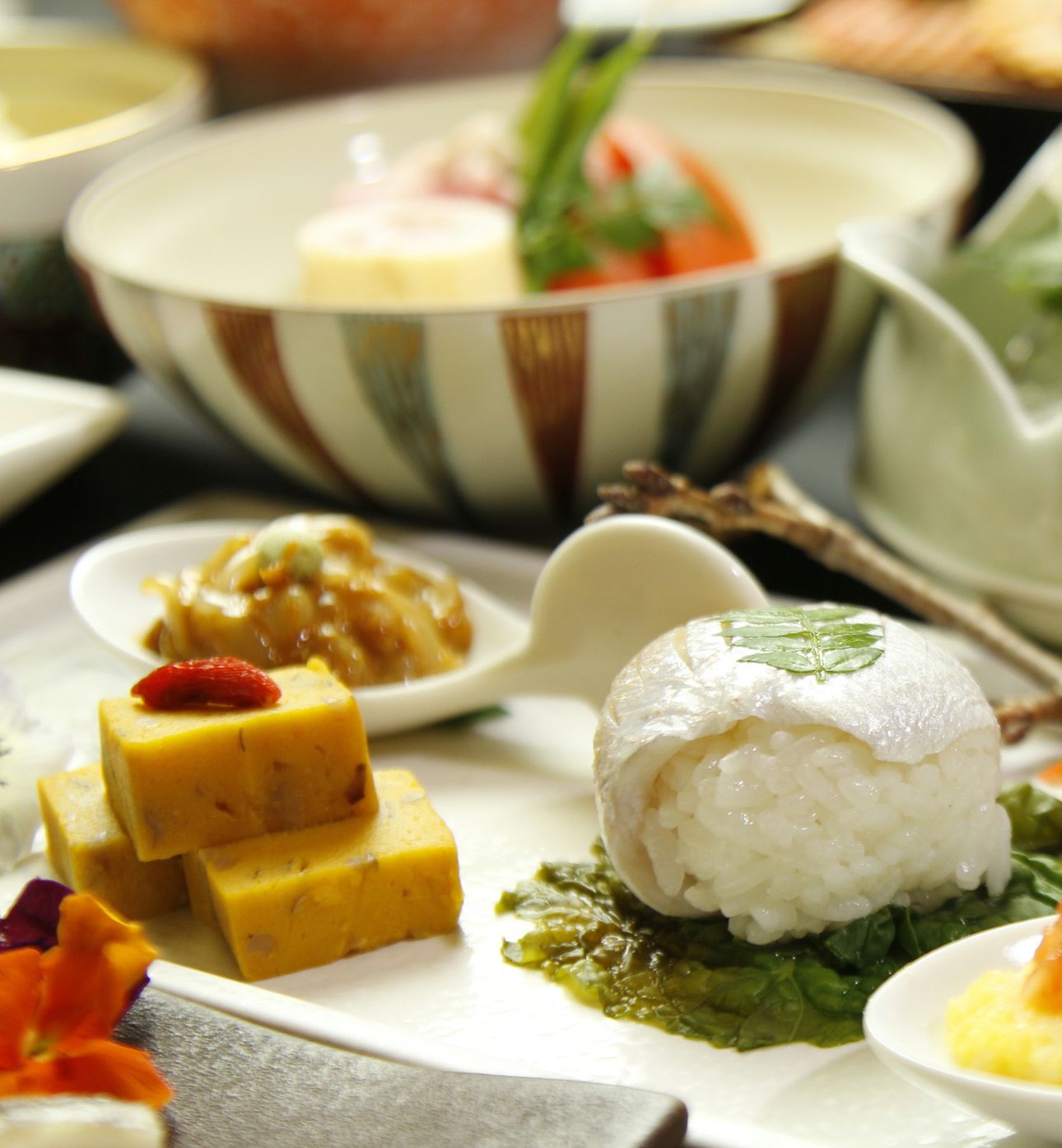 A variety of dishes including rice, tofu, and leafy greens, suggesting a meal setting.