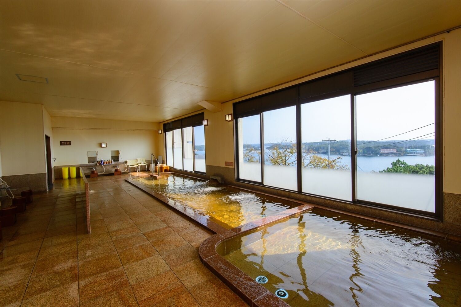 A long indoor swimming pool with clear windows and a view of a body of water.