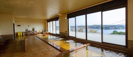 A long indoor swimming pool with clear windows and a view of a body of water.