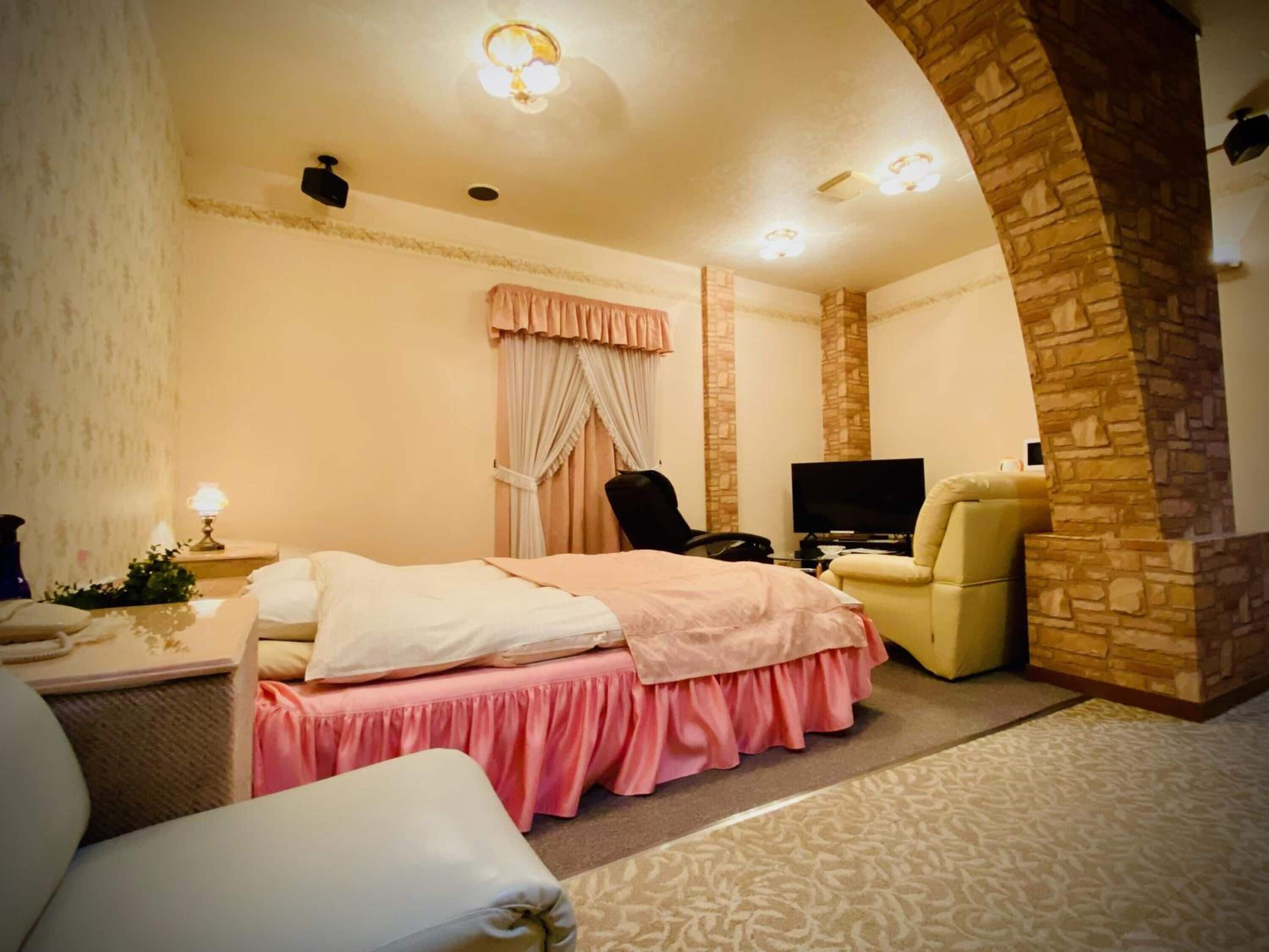Une chambre d’hôtel avec un lit, une chaise, une télévision et un mur décoratif en pierre.