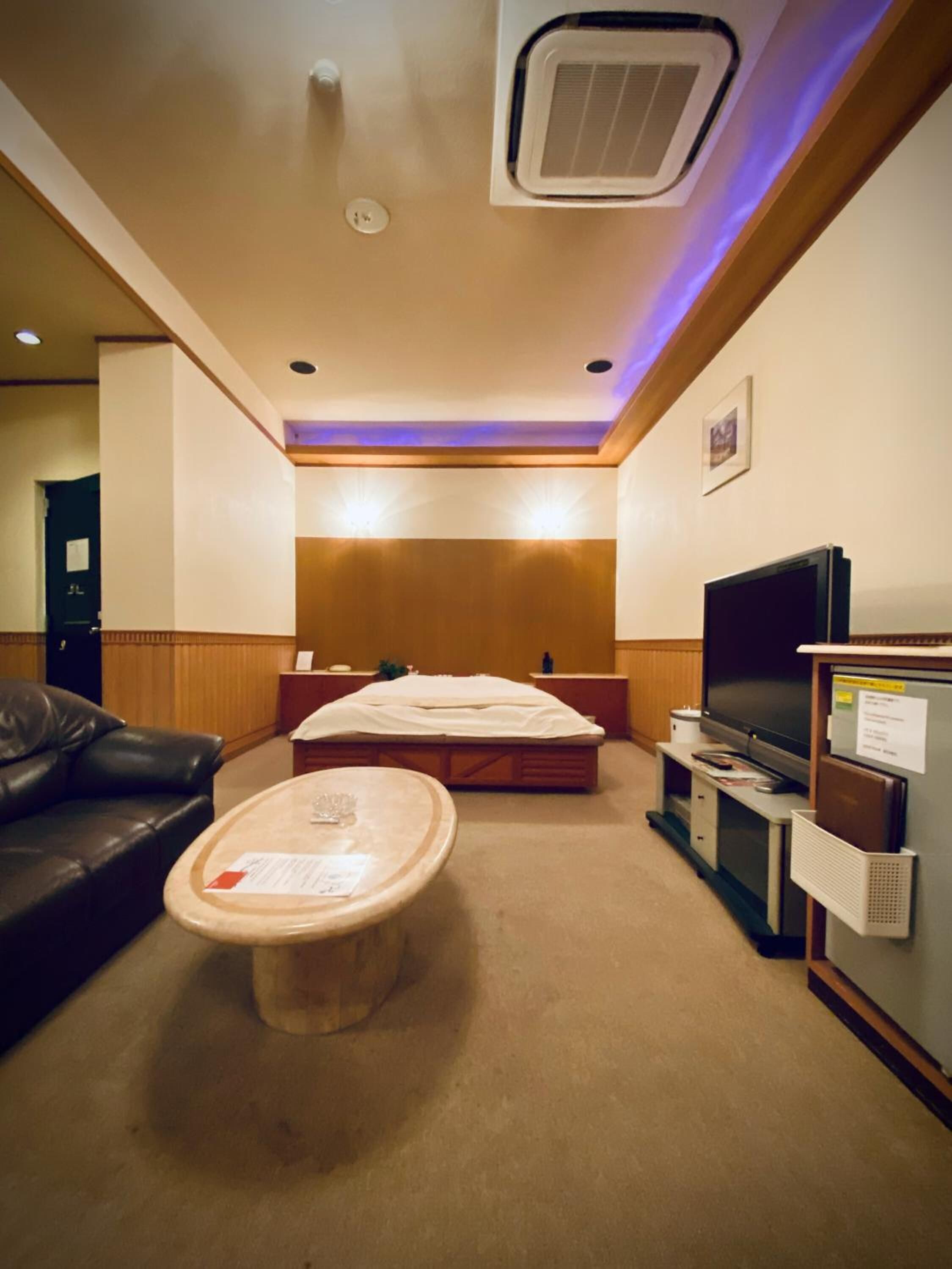 A hotel room with a bed, a TV, a sofa, and a small table.