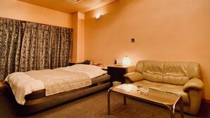 Een hotelkamer met een bed, een slaapbank, een bijzettafeltje en een plafond met inbouwspots.