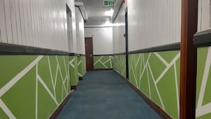 A hallway with green and white walls, a blue carpet, and an exit sign. - 999 Hotel (Angeles City)