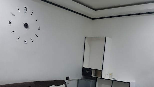 A bedroom with a bed, a nightstand, a dresser, a mirror, and a wall clock. - 999 Hotel (Angeles City)