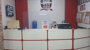A reception desk with a large number sign, a water cooler, a computer, and a bulletin board. - 999 Hotel (Angeles City)