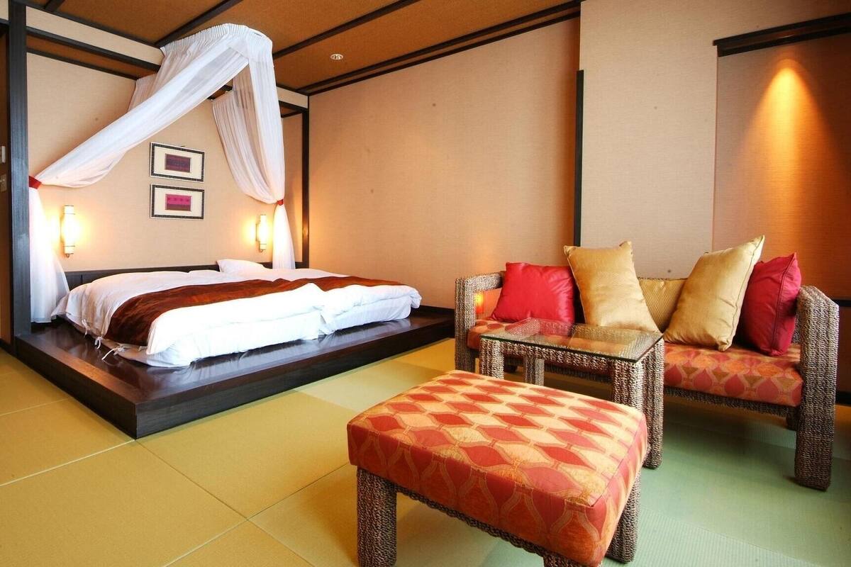 A hotel room with a bed, a sofa, a chair, and a small table.