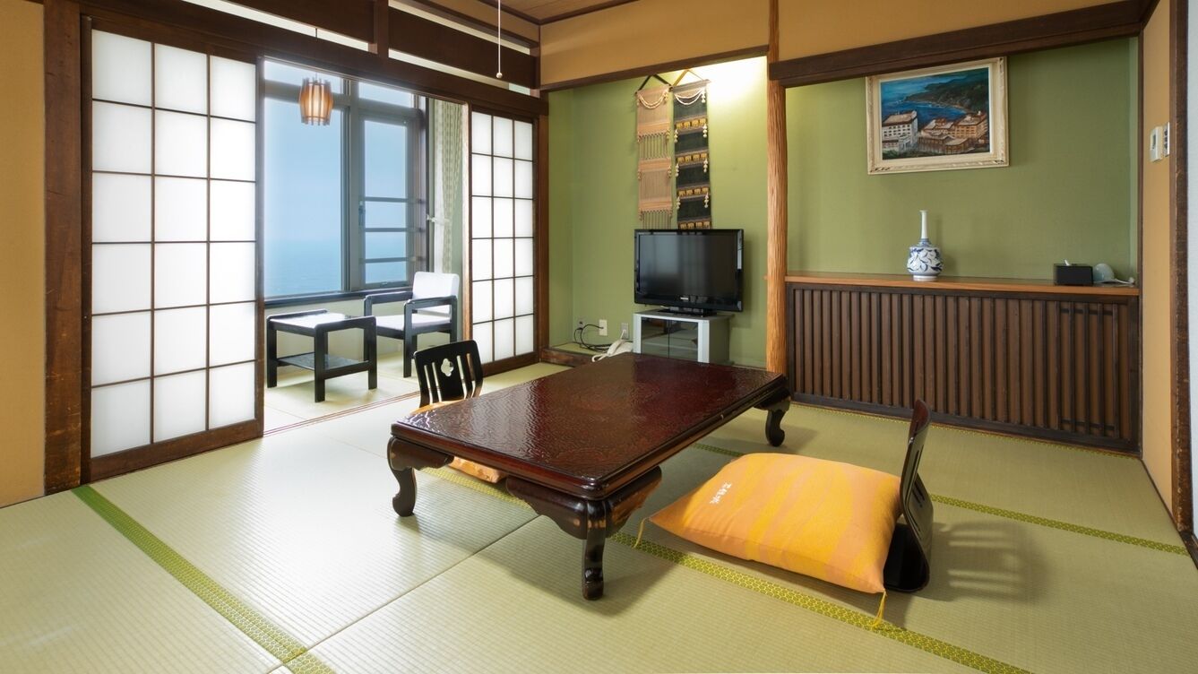 A tatami mat room with a tatami mat table, a television, and a traditional Japanese painting.