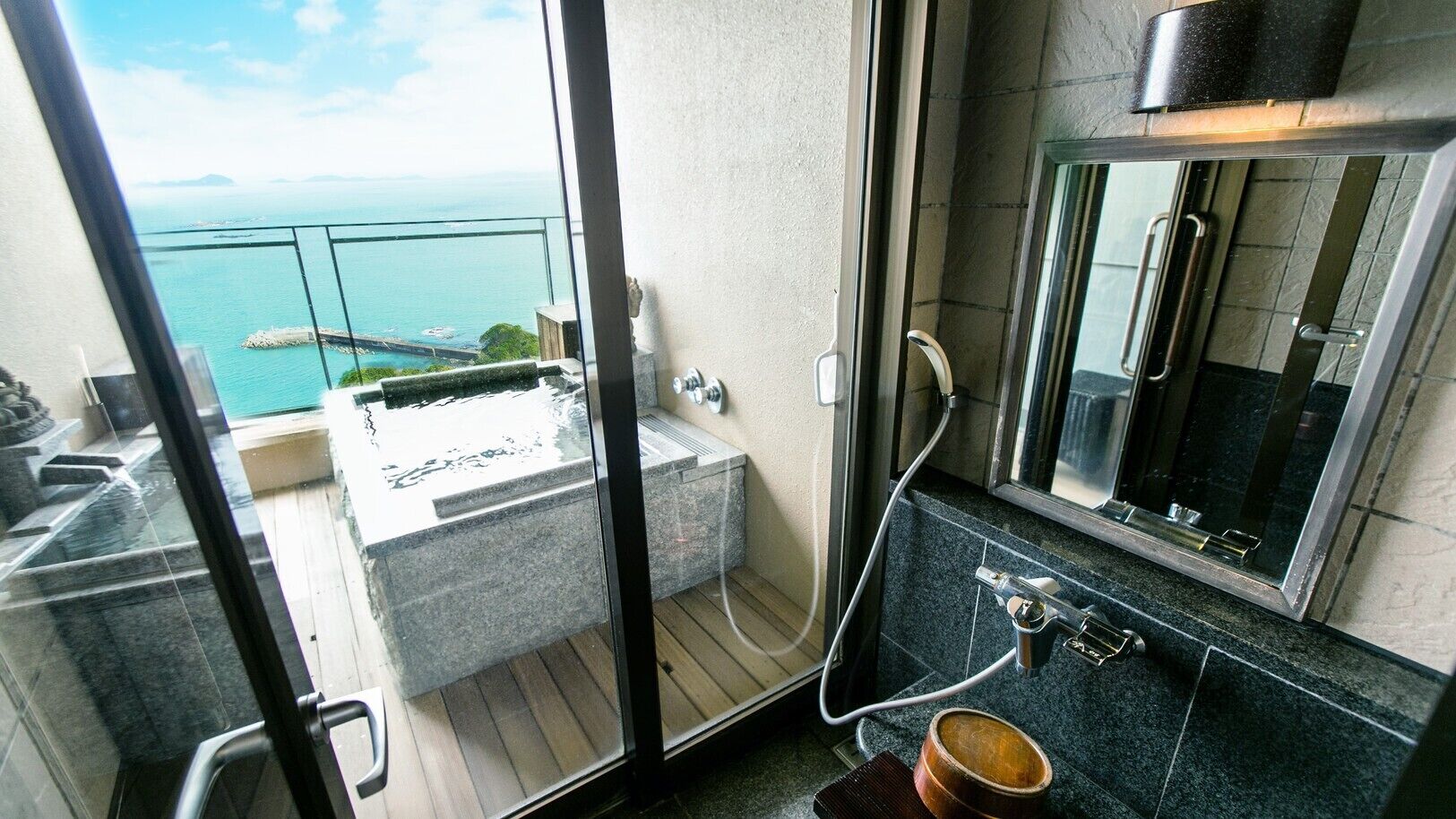 A balcony with a hot tub, a shower, and a sink with a mirror.