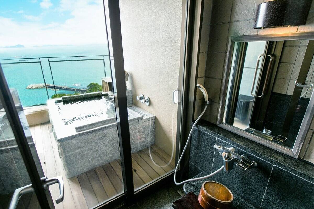 A balcony with a hot tub, a shower, and a sink with a mirror.