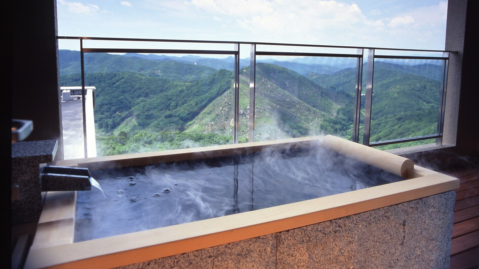 A hot tub with a view of a mountainous landscape through large windows.