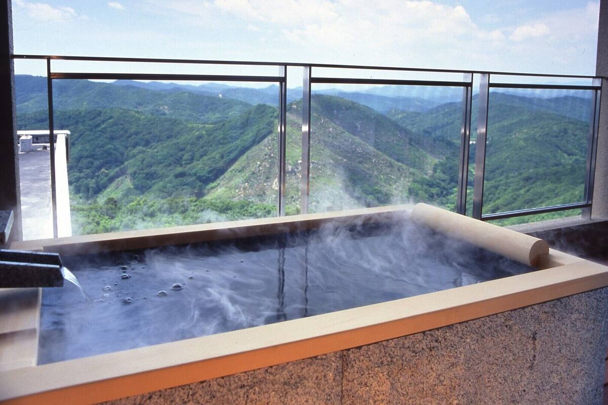 A hot tub with a view of a mountainous landscape through large windows.