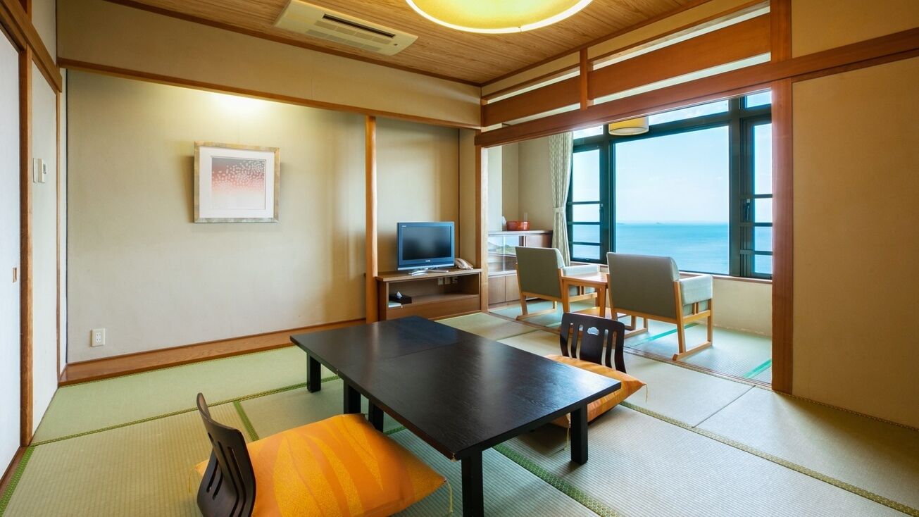 A traditional Japanese room with tatami flooring, a low table, and chairs.