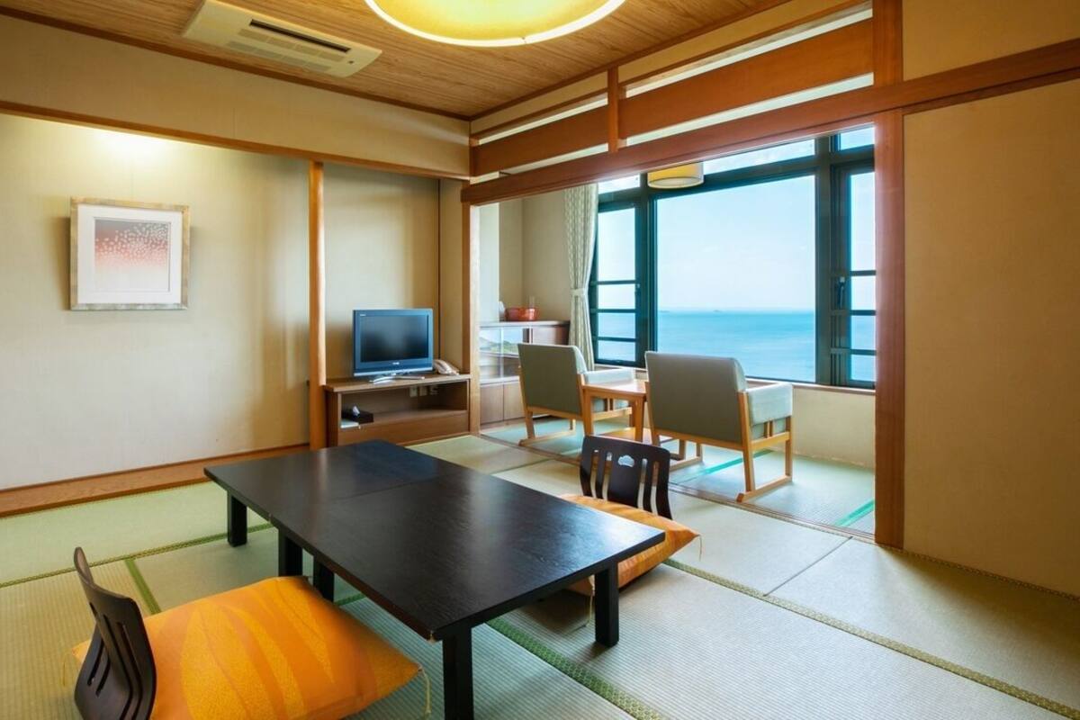 A traditional Japanese room with tatami flooring, a low table, and chairs.