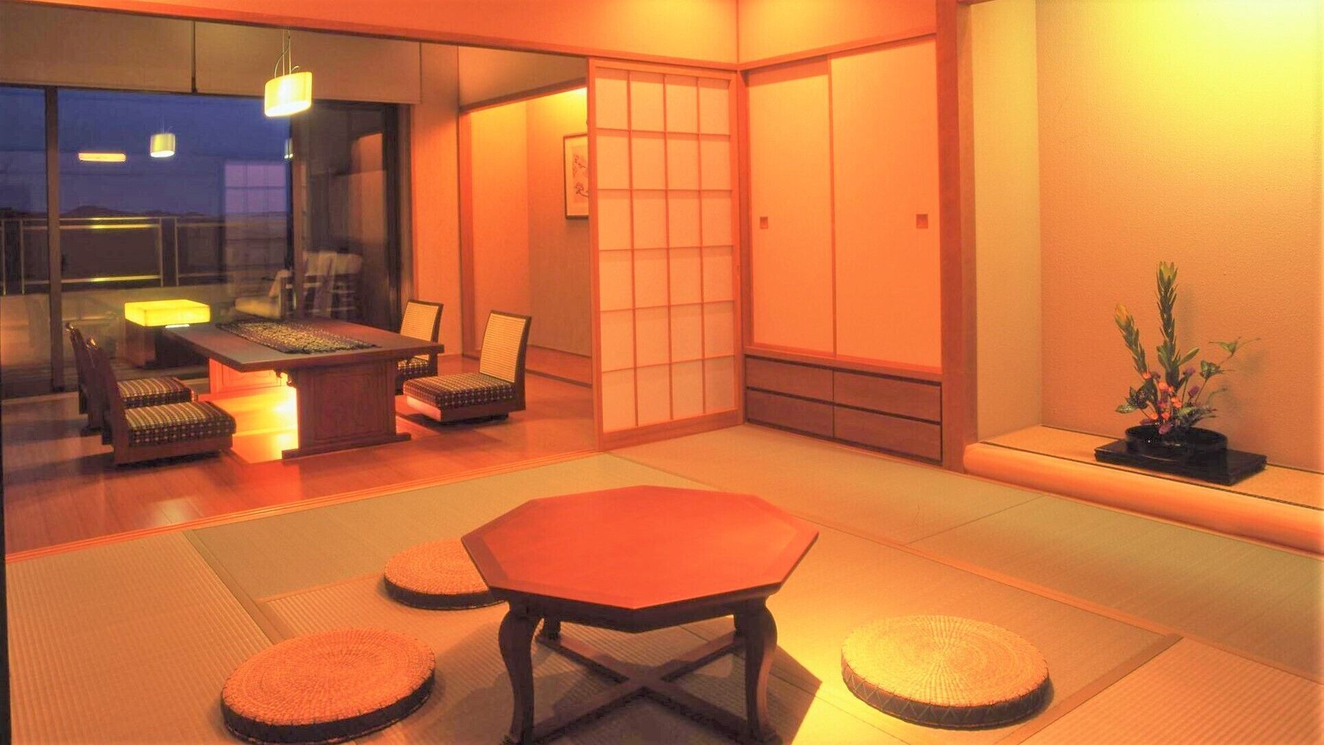 A traditional Japanese room with tatami flooring, a low table, and chairs.