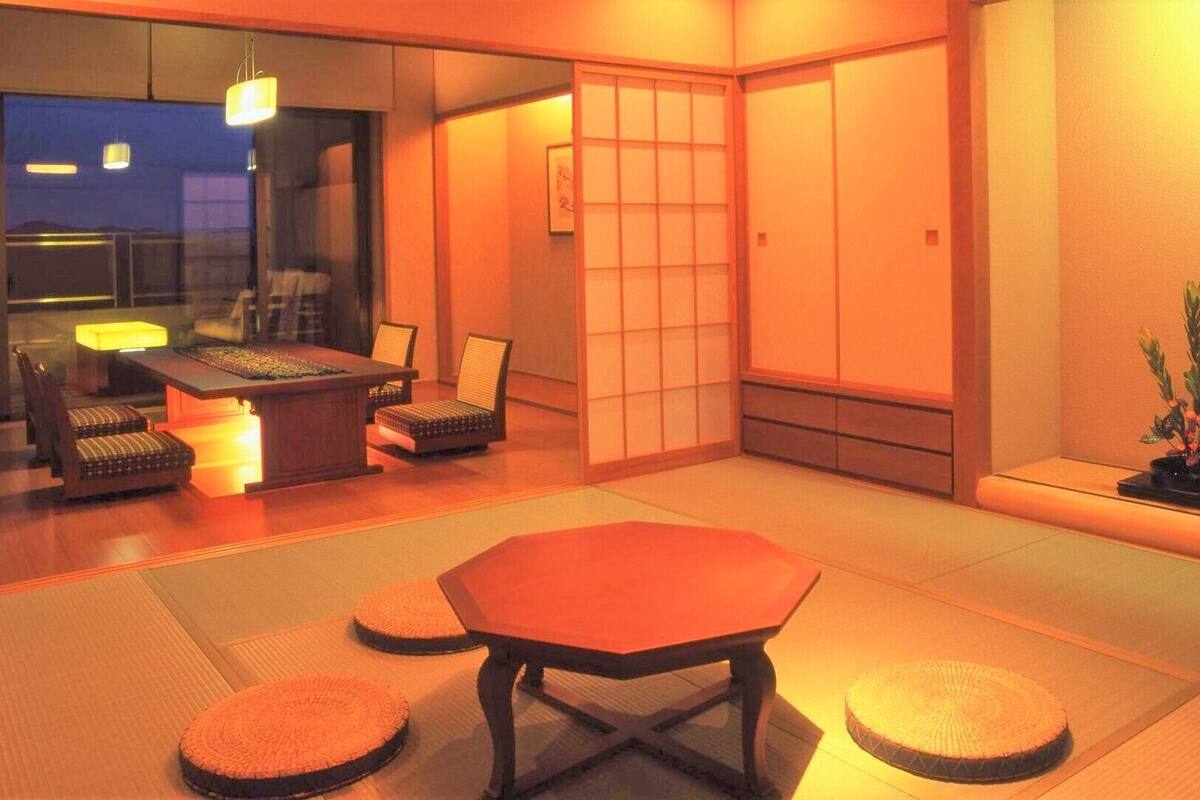 A traditional Japanese room with tatami flooring, a low table, and chairs.
