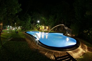 A swimming pool with a fountain, surrounded by a stone deck and greenery. - Villa 80 (Bentota)