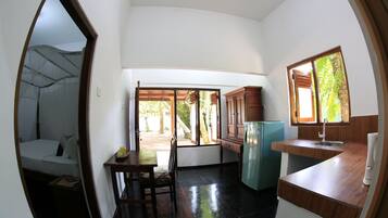 A compact hotel room with a bed, a small table, and a kitchenette.