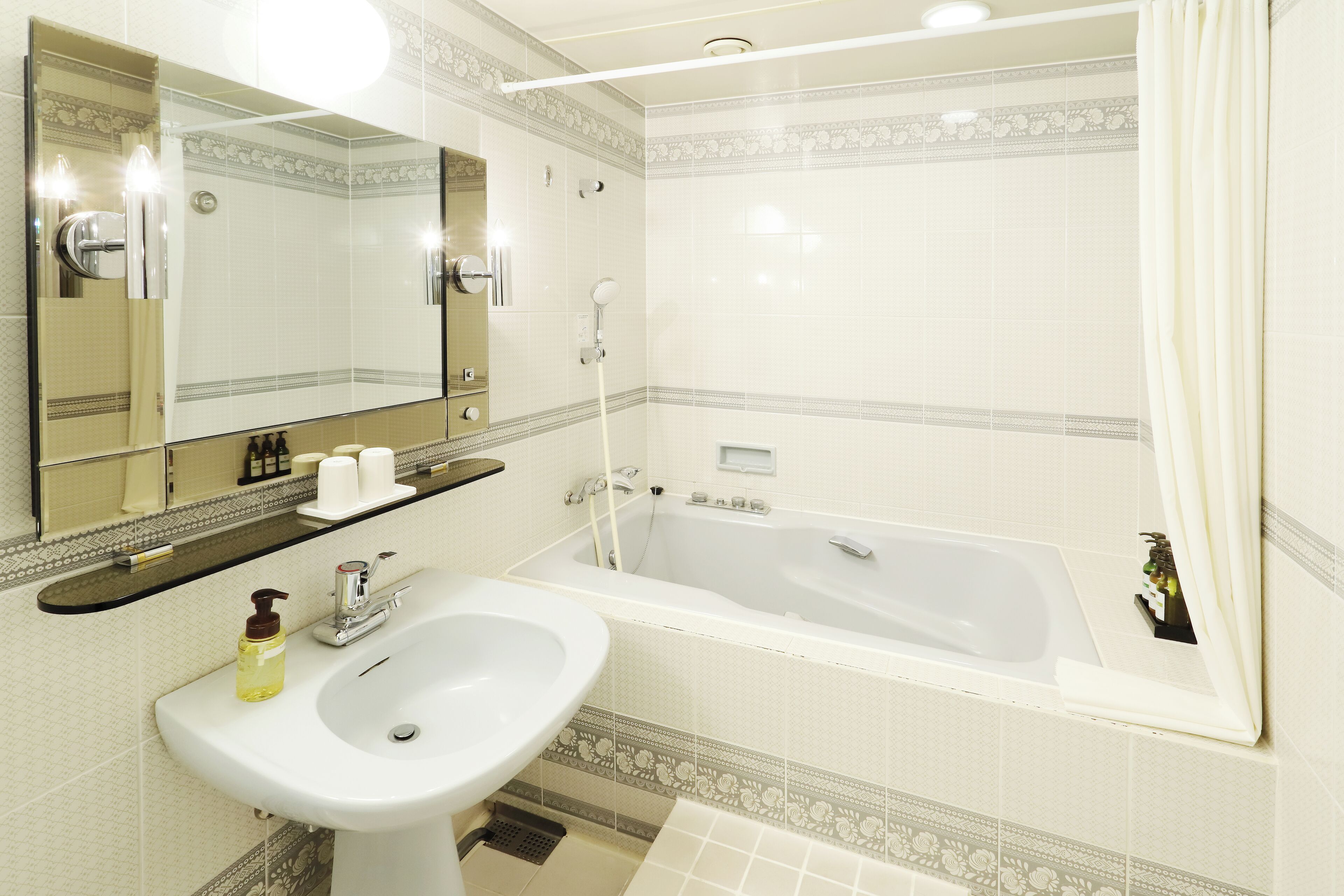 A bathroom with a sink, mirror, and bathtub.