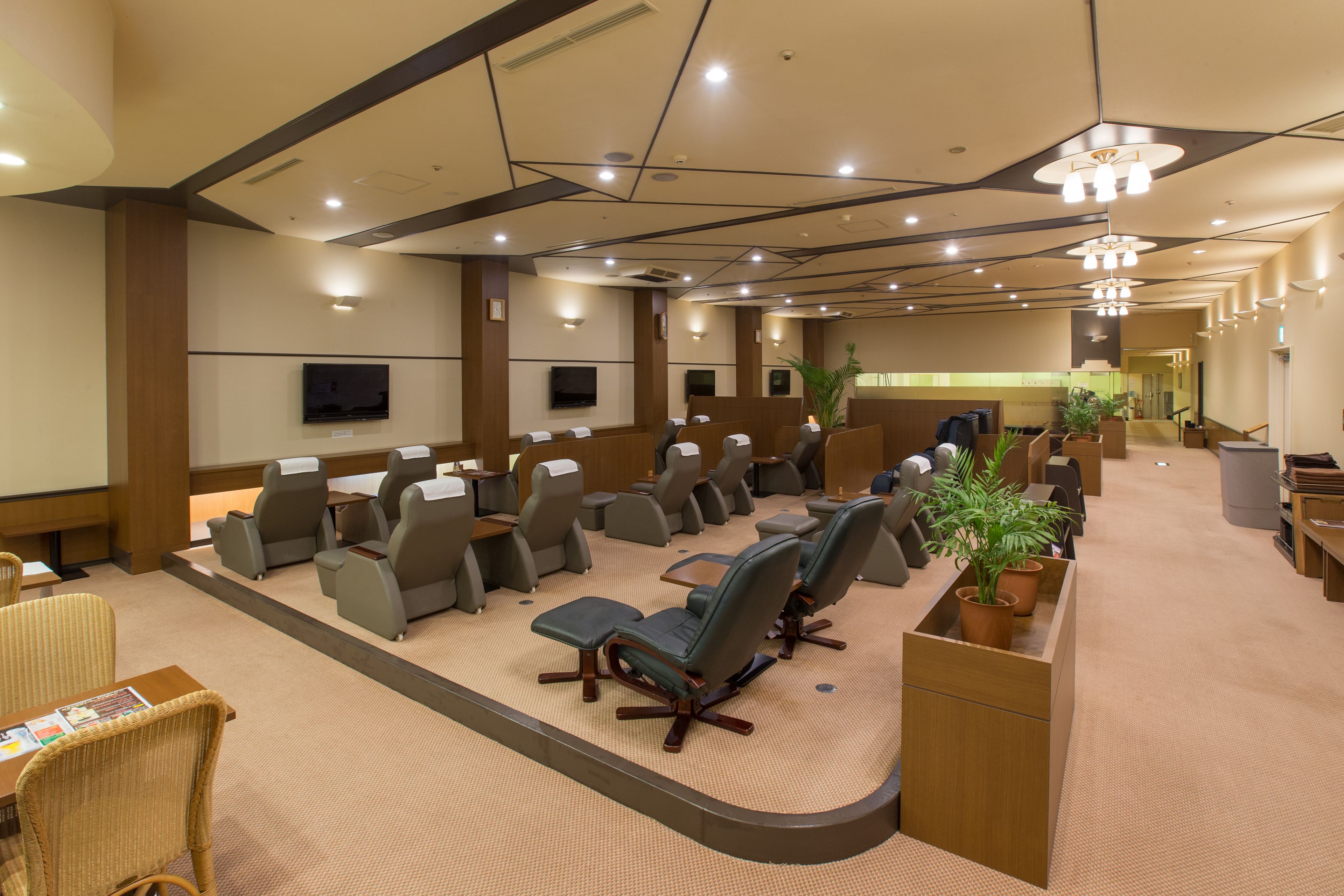A conference room with rows of chairs, a large screen, and a reception desk.
