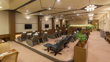 A conference room with rows of chairs, a large screen, and a reception desk.