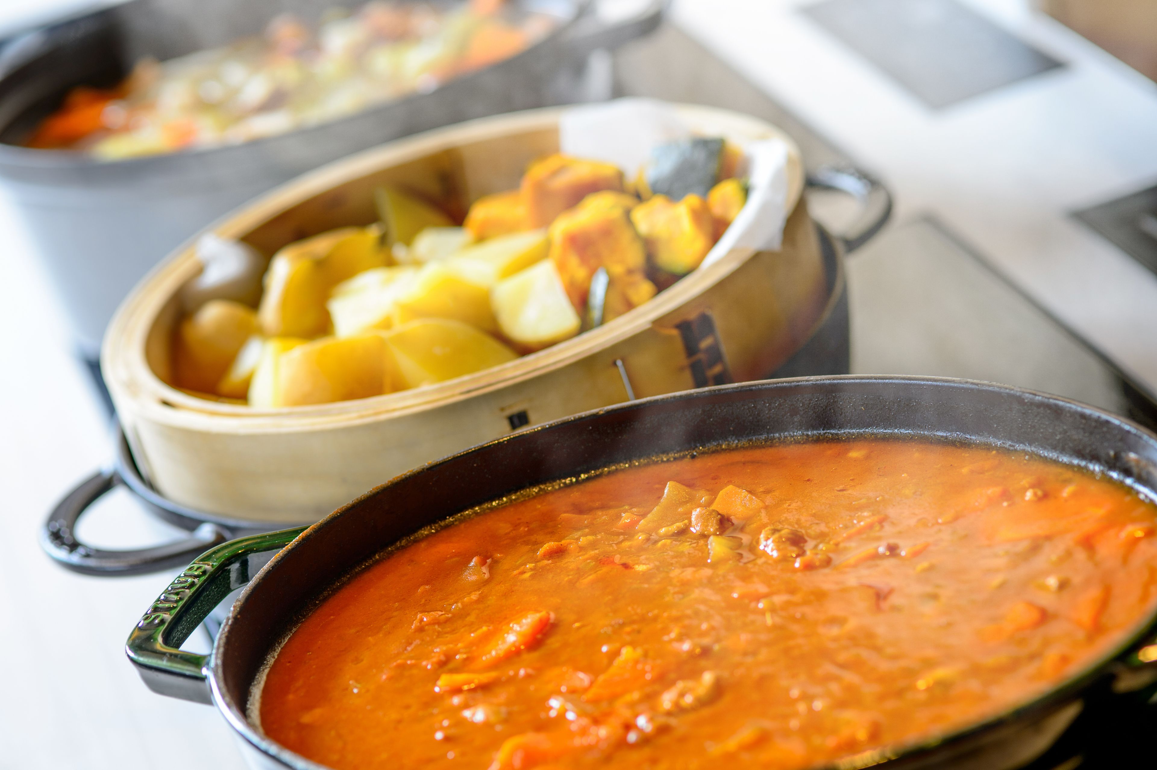 Dos ollas de comida, una con papas y otra con un guiso rojo.