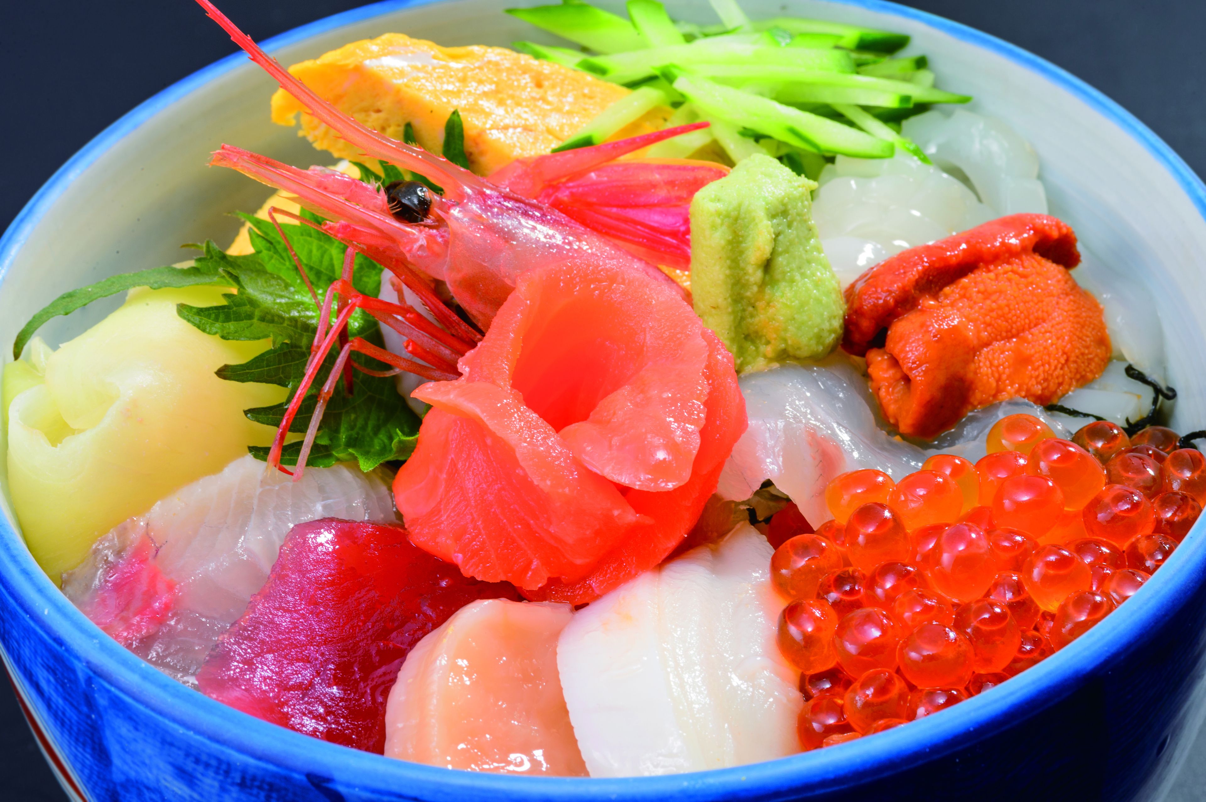 Una ciotola di sashimi con diversi tipi di pesce e guarnizioni.