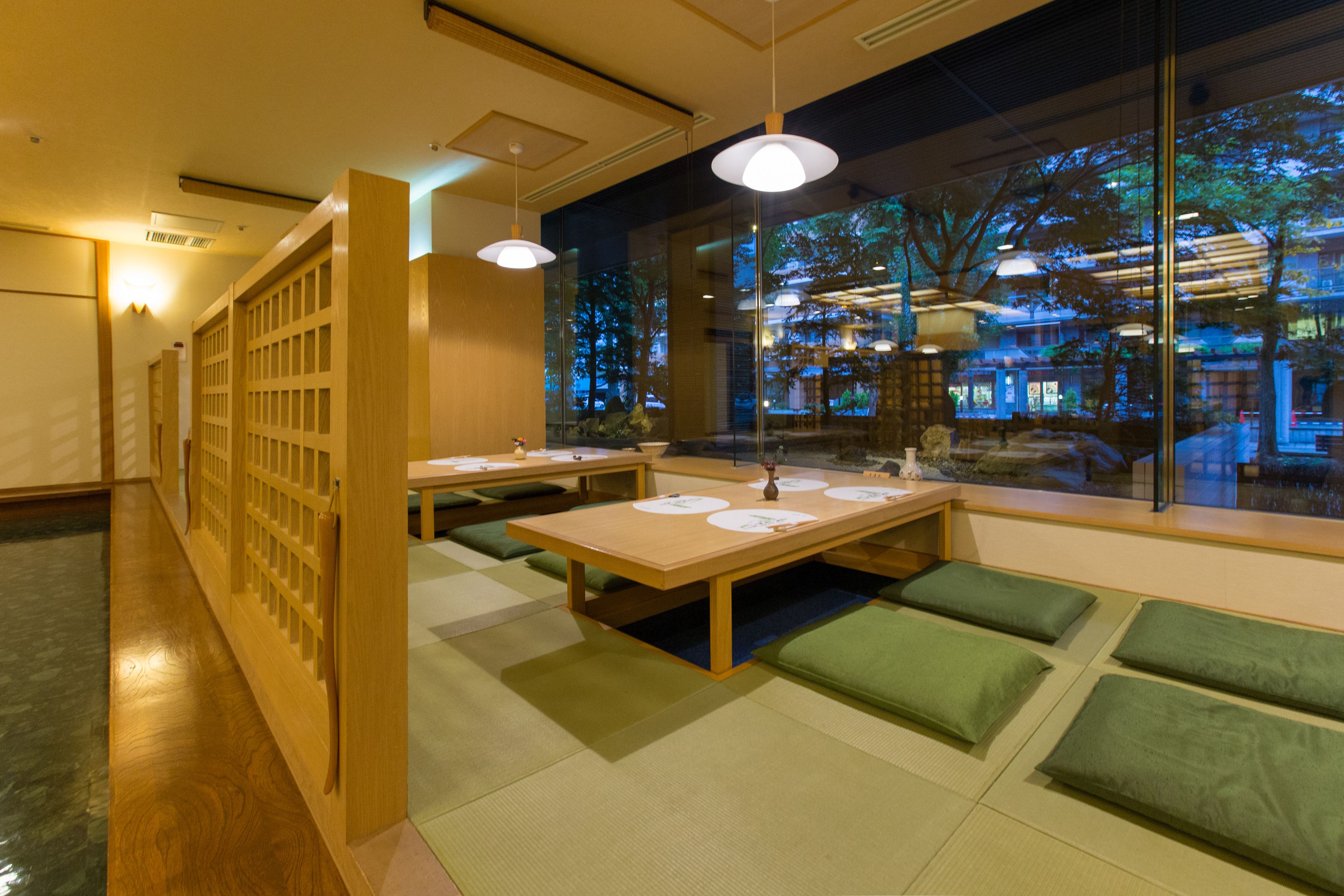 Ein modernes Interieur mit einem langen Tisch, grünen Kissen und Blick ins Freie.