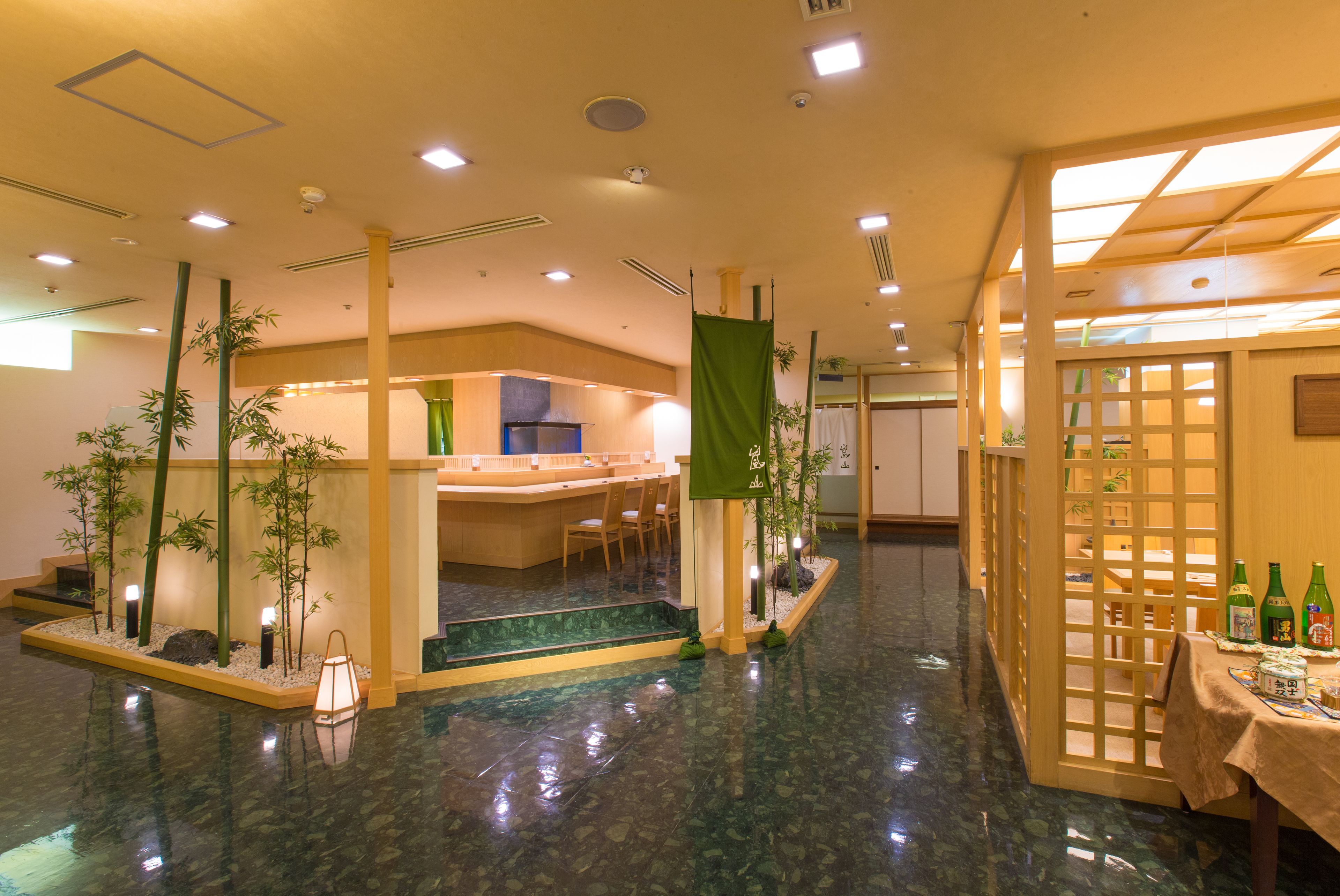 Um saguão de hotel com balcão de recepção, área de estar e exposição de garrafas.