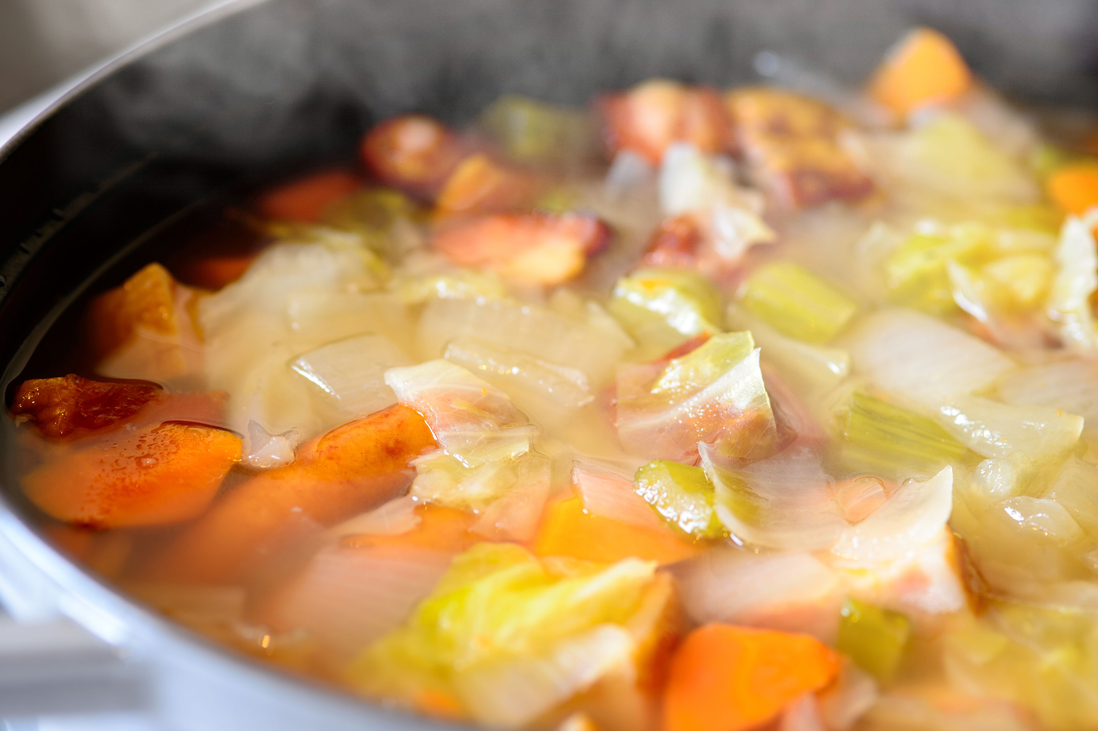 A close-up of a soup with various vegetables and meat.