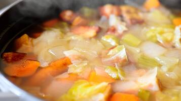 A close-up of a soup with various vegetables and meat.