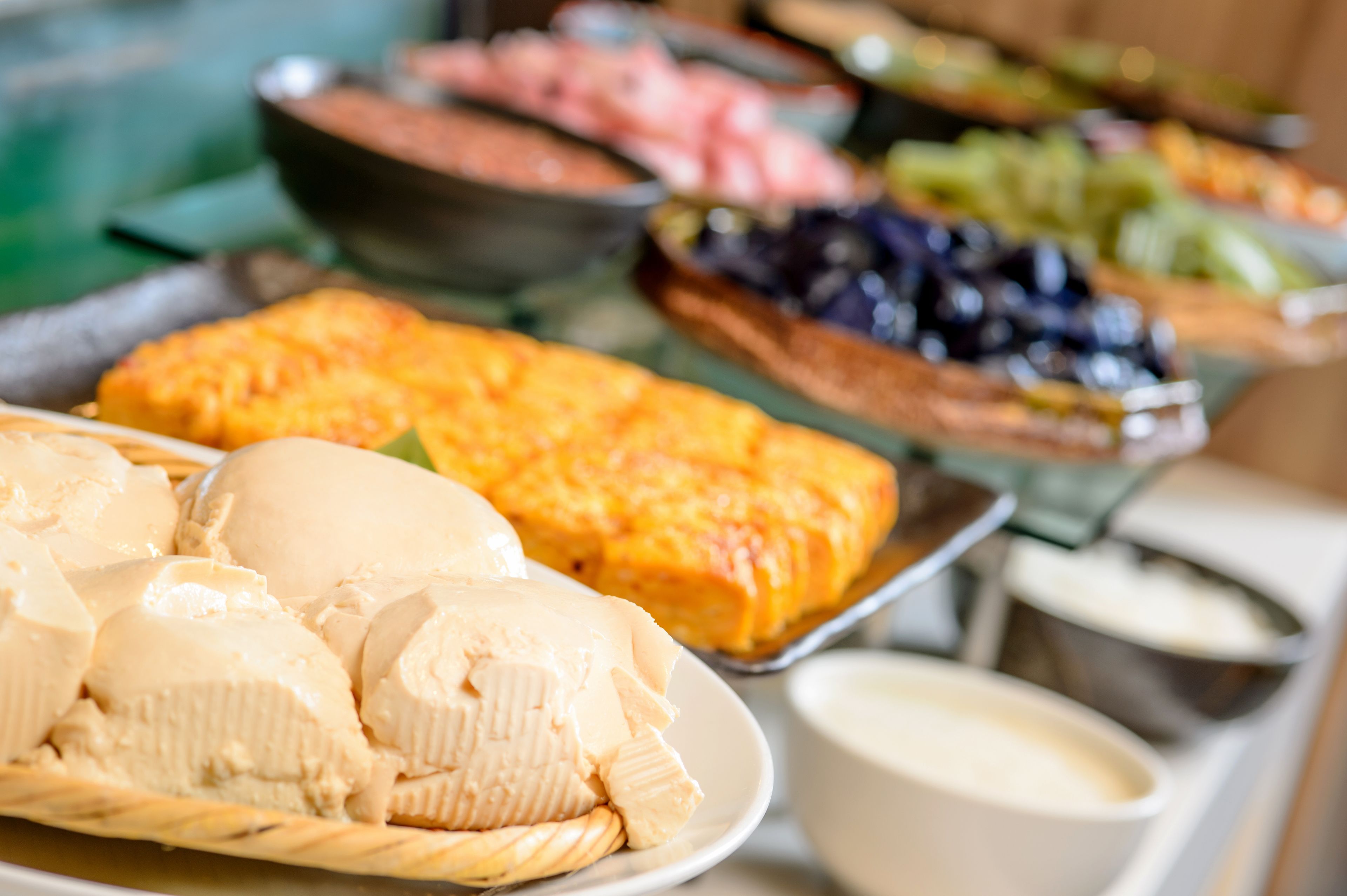 Un buffet con diversi alimenti, tra cui un piatto di banane, un vassoio di formaggi e una ciotola di frutta.