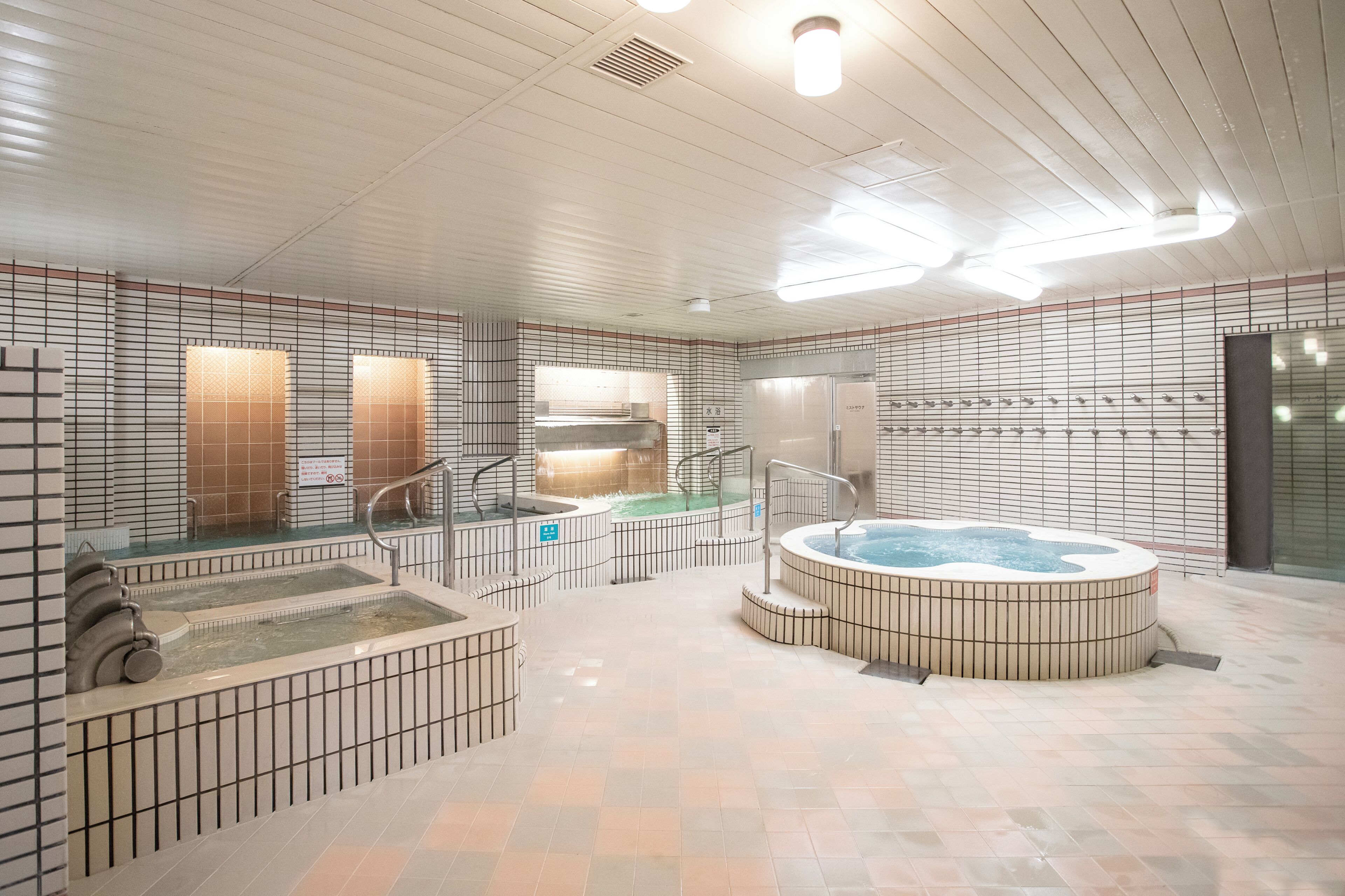 Un espace spa moderne doté d’un bain à remous, de plusieurs saunas et d’un sol carrelé.