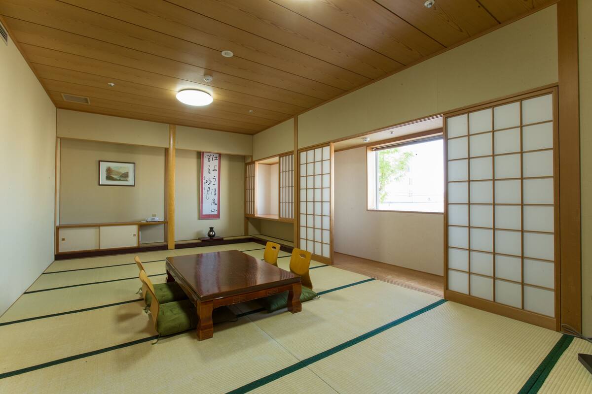 A traditional Japanese room with tatami flooring, a wooden table, and sliding doors.