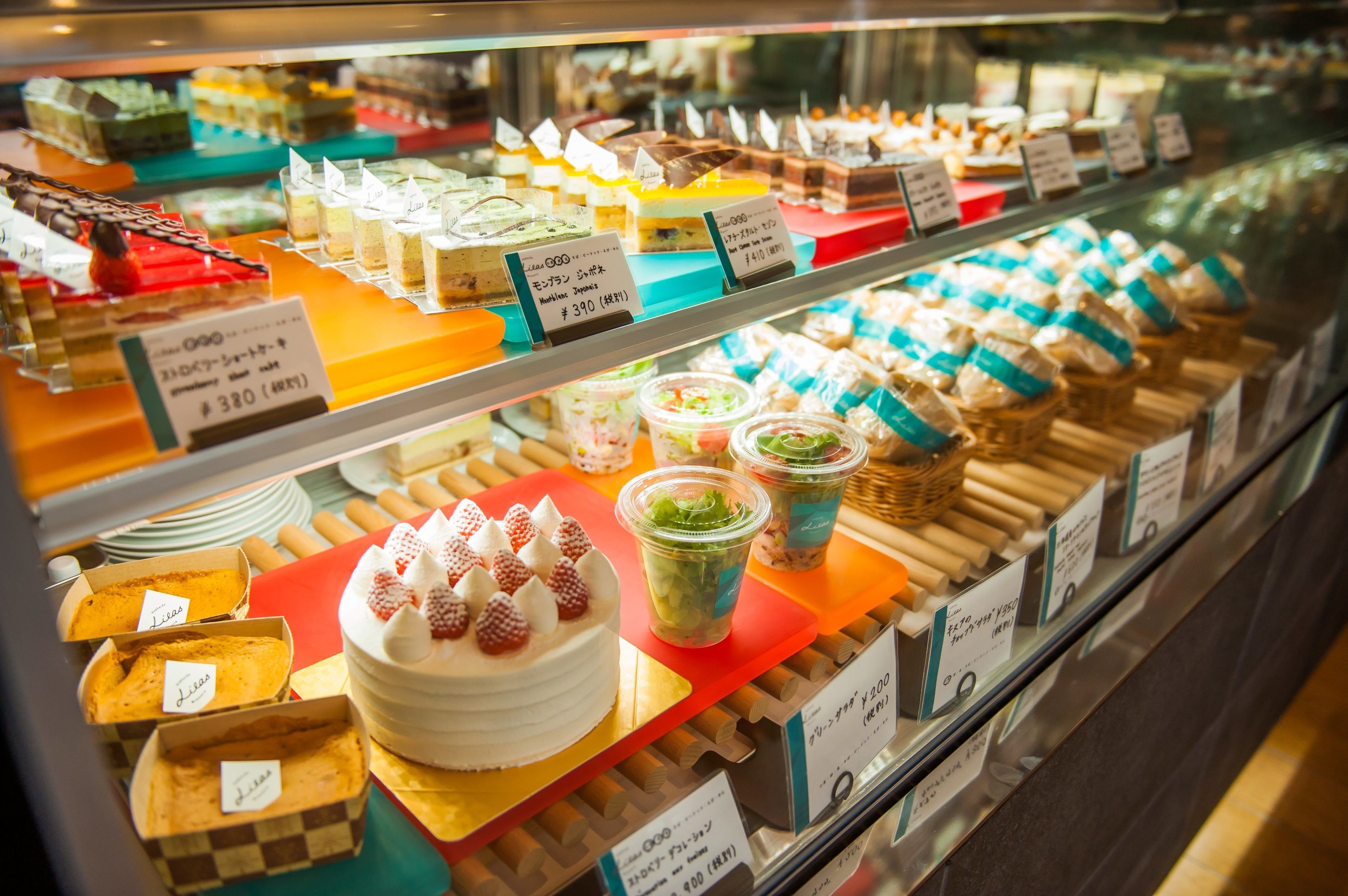 Variedad de postres y pasteles expuestos en una vitrina con precios.