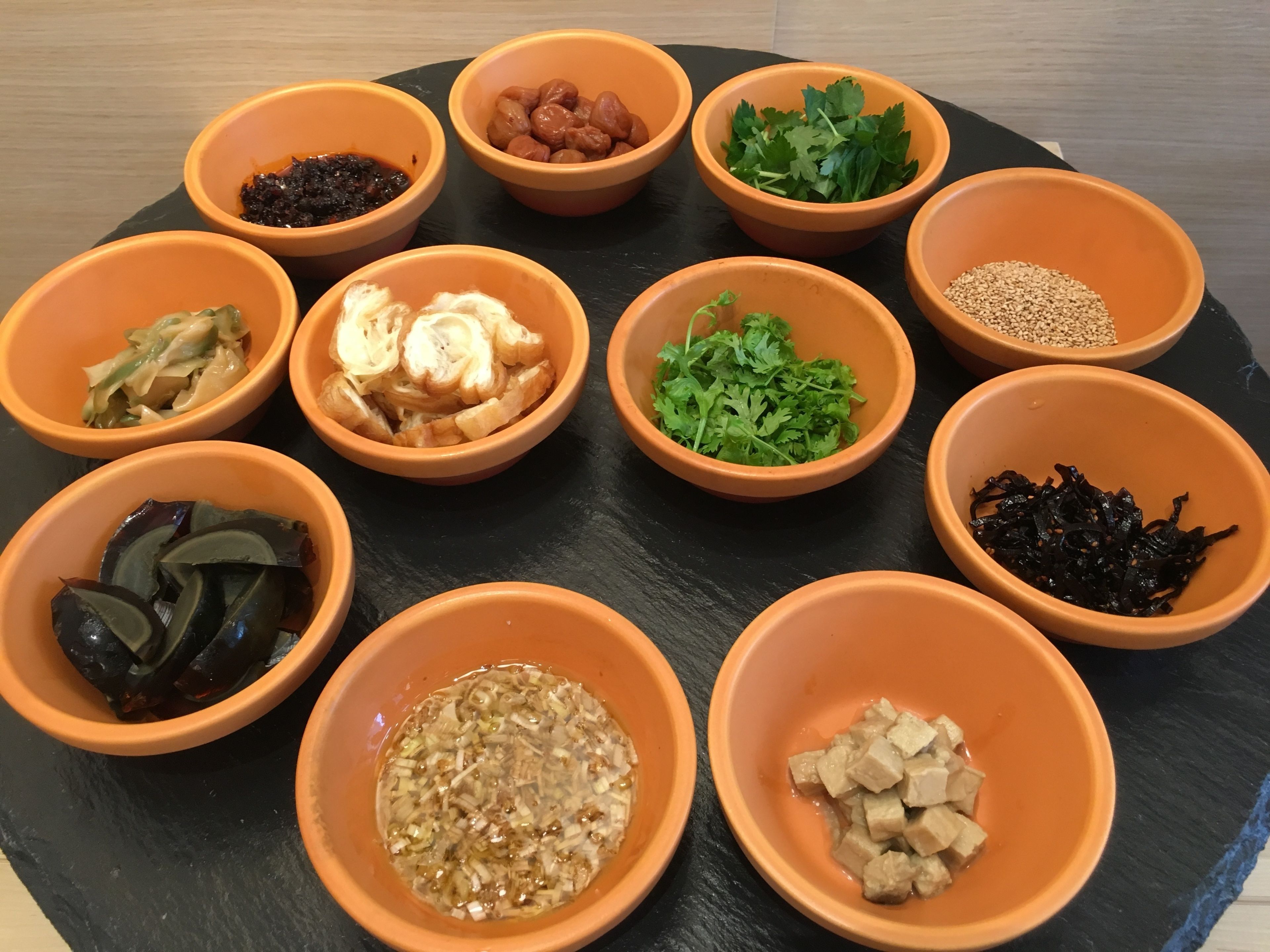 Diversos alimentos em tigelas de barro dispostos sobre uma superfície preta.