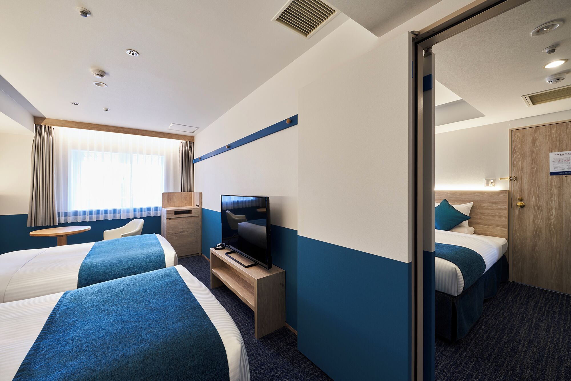 Une chambre d’hôtel avec deux lits, un bureau, une télévision et un miroir.
