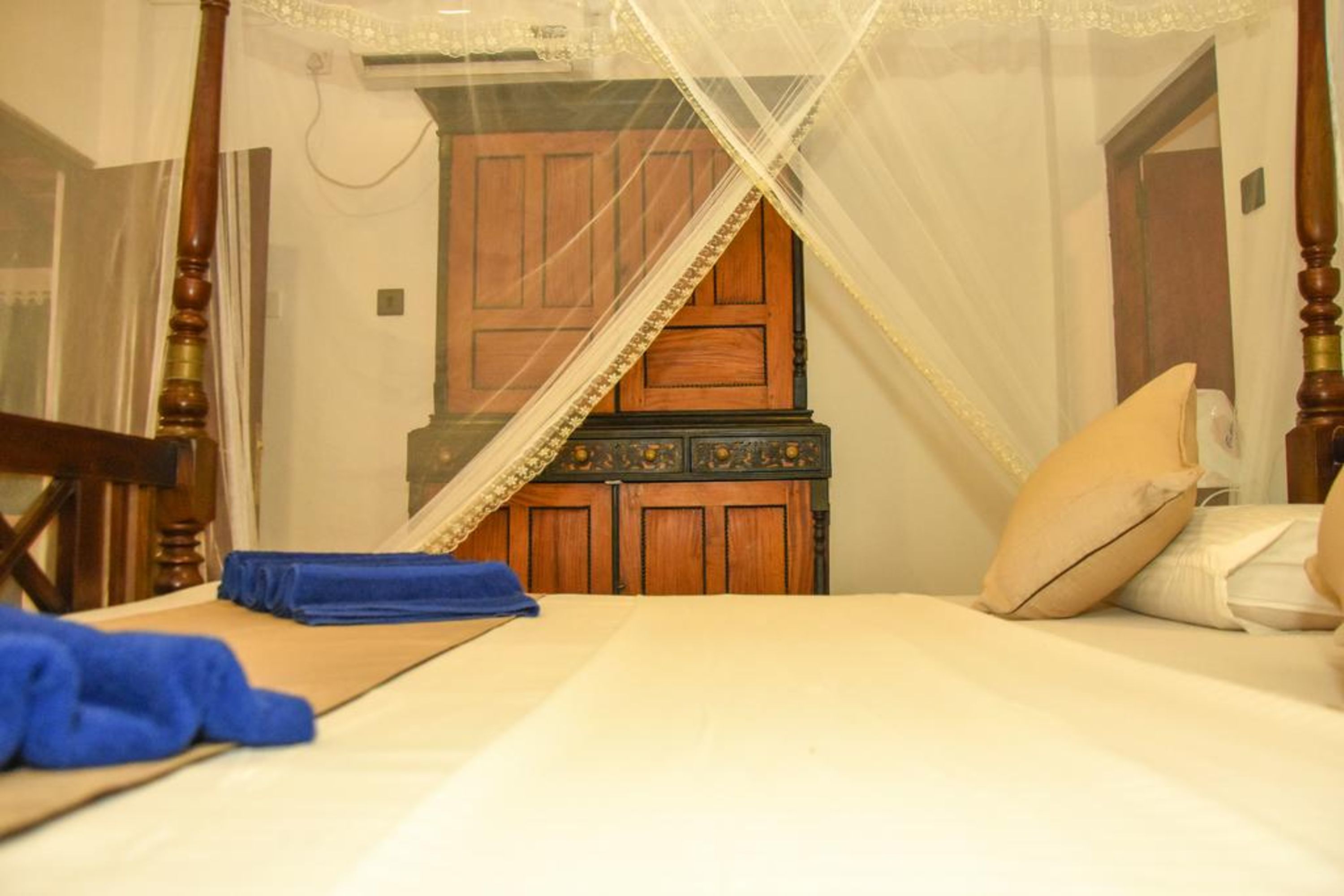 Une chambre à coucher avec un lit à baldaquin, une armoire en bois et une couvre-lit assorti.