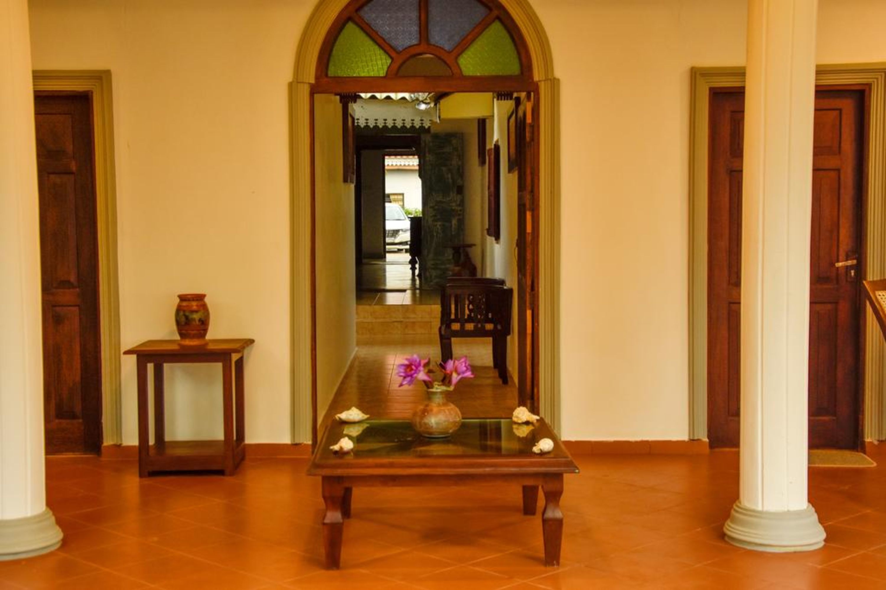 Un couloir avec une table en bois, un vase de fleurs et un miroir.