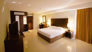 A hotel room with a large bed, bedside tables with lamps, a wardrobe, and a television. - Summer Spring Hotel (Pattaya)