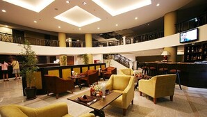 A spacious lobby with a high ceiling, multiple seating areas, a bar, and a staircase leading to an upper level. - Summer Spring Hotel (Pattaya)