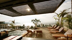 A poolside area with lounge chairs and a view of the sea. - Summer Spring Hotel (Pattaya)