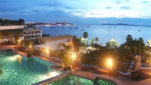 A resort pool area with multiple pools, a beach view, and a well-lit deck. - Summer Spring Hotel (Pattaya)
