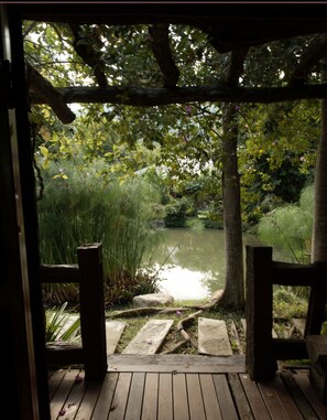 A wooden deck leading to a pond surrounded by lush greenery and trees. - Bulun Buri Resort (Hang Dong)