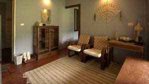 A cozy living room with a wooden ceiling, a glass cabinet, two chairs, a small table, and a decorative wall hanging. - Bulun Buri Resort (Hang Dong)