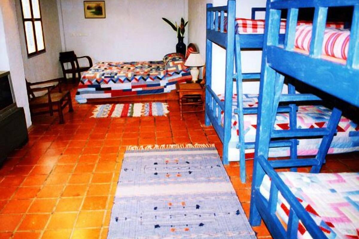 A room with bunk beds, a patterned rug, and a chair.