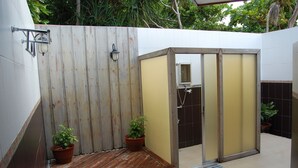 Um banheiro com piso de madeira, parede branca e porta amarela.