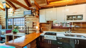 Eine rustikale Kücheneinrichtung im Chalet-Stil mit Holzwänden, einer zentralen Kochinsel und einem Herd.